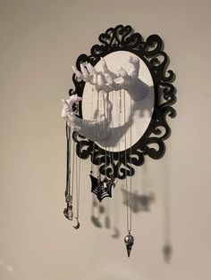 a black and white clock hanging from the side of a wall next to a mirror