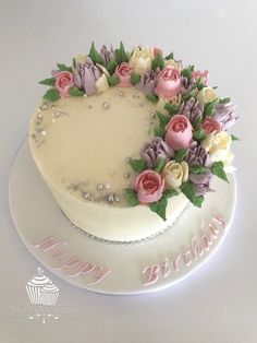 a birthday cake decorated with pink and white flowers