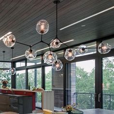 an open kitchen and dining area with large windows, glass doors, and chandelier