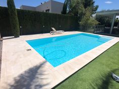 an empty swimming pool in the middle of a backyard with grass and bushes around it