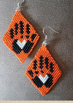 an orange and black beaded tiger earrings with silver earwires on a gray surface