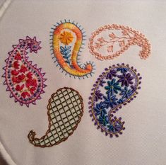 an embroidered design on a white cloth with flowers and paisleys in different colors, including the letter j