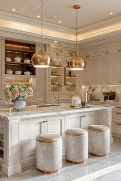 an elegant kitchen with marble counter tops and gold pendant lights hanging from the ceiling over the island