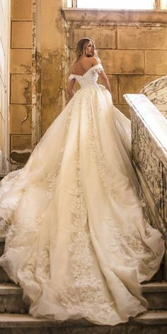 a woman in a wedding dress is walking up some stairs with her hand on her hip