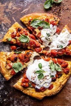 a pizza topped with tomatoes, cheese and spinach on top of a piece of parchment paper