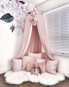 a pink canopy bed in a bedroom with flowers on the wall and white fluffy rugs