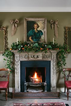 a living room filled with furniture and a fire place covered in greenery next to a painting