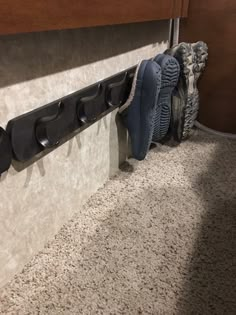 three pairs of shoes are hanging on the wall next to a pair of boot holders