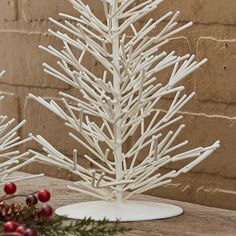 a white christmas tree sitting on top of a wooden table next to a brick wall