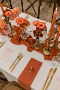 the table is set with orange napkins and gold cutlery, which are decorated with flowers