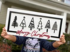 a young boy holding up a sign that says merry christmas