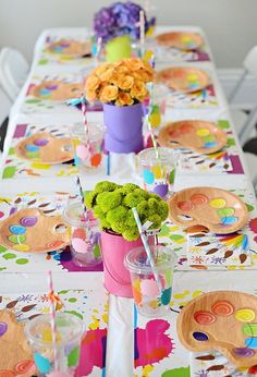 the table is set with colorful plates and flowers