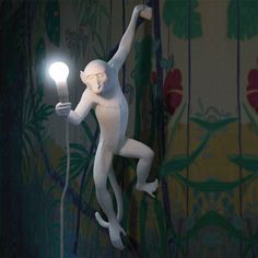 a white monkey statue holding a lamp in the air