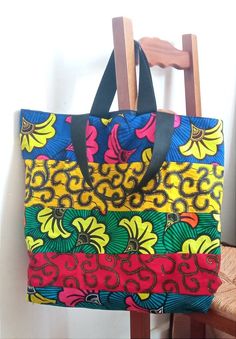 a colorful handbag sitting on top of a wooden chair next to a white wall