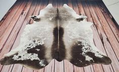 two brown and white cows skin rugs on wooden floor next to building with sky in background