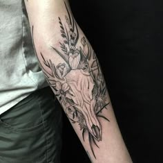 a man's arm with a deer head and flowers tattooed on the left forearm