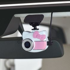 a hello kitty camera attached to the side of a car mirror with a pink bow on it