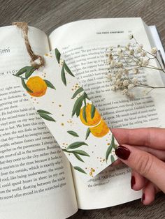 a bookmark with oranges on it is held in front of an open book