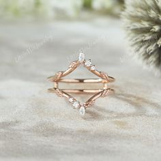 a rose gold ring with three diamonds on it and a pine branch in the background