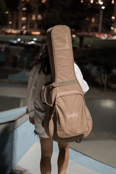 a woman carrying a guitar case on her back