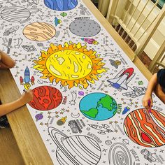 two children are sitting at a table with an image of the sun and planets on it