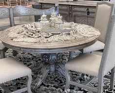 an ornate dining table with four chairs around it