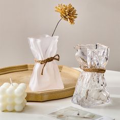 a glass vase with a flower in it on a tray next to candles and a candle holder