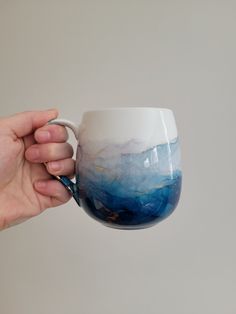 a hand holding a blue and white coffee cup