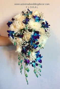 a bridal bouquet with white roses and blue orchids is held by a woman's hand