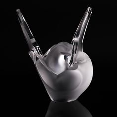 a glass vase with two spoons in the shape of a bird on black background