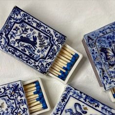 four matchboxes with matches in them on a white tablecloth, one is blue and the other has an animal design