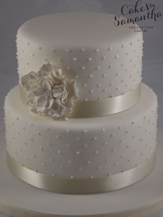 a three tiered white wedding cake with flowers on top