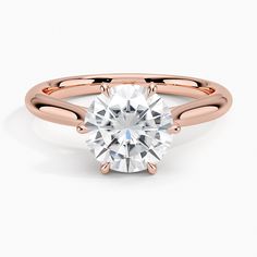 a rose gold engagement ring with a round cut diamond in the center, on a white background