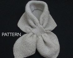 a white knitted scarf with a knot on the front and back ends, sitting on a black surface