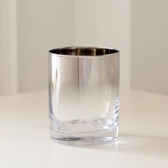 an empty glass sitting on top of a white table next to a wall and floor