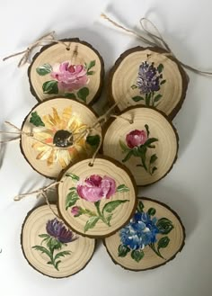 several pieces of wood with flowers painted on them hanging from twine strings in the shape of circles