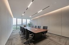 an empty conference room with large wooden table and black chairs