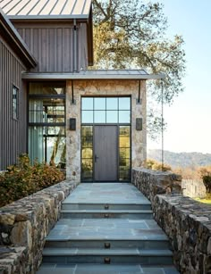 a house with stone steps leading up to the front door and entry way that has glass windows