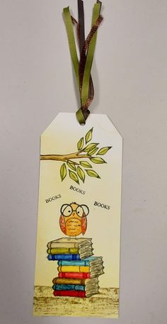 a bookmark with an owl sitting on top of a stack of books