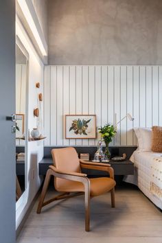 a bed room with a neatly made bed next to a chair and a mirror on the wall