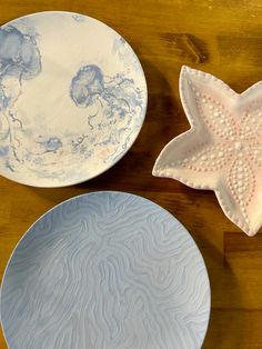 two plates with designs on them sitting on a table next to a starfish dish