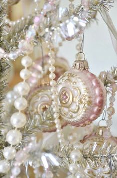 some ornaments are hanging from a tree with white and pink beads on it's branches