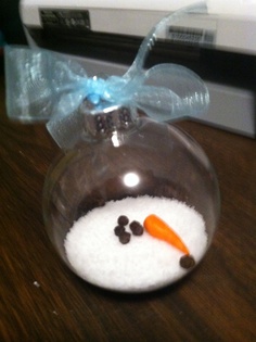 a glass ornament with a carrot and snowman in it on a table