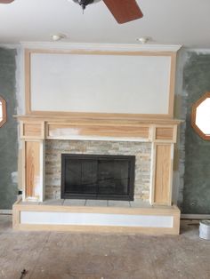 an empty living room with a fireplace and ceiling fan