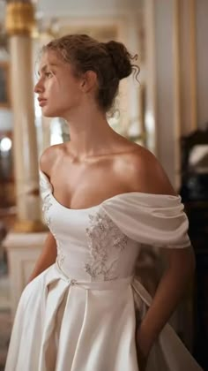 a woman in a white wedding dress posing for the camera with her hands on her hips