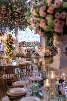 the tables and chairs are set up for a formal function with flowers hanging from the ceiling