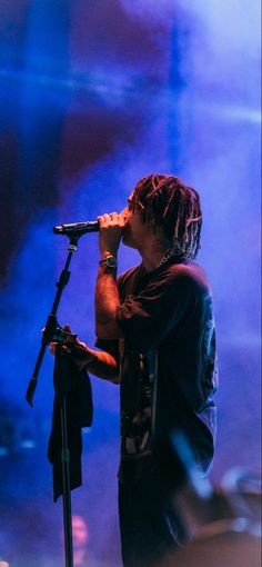 a man with dreadlocks on his head singing into a microphone at a concert