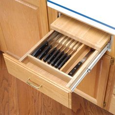 an open drawer in the middle of a kitchen cabinet with utensils and knives