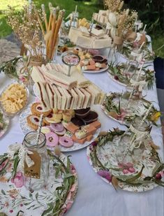 a table topped with plates covered in sandwiches and desserts