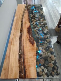 a table that has some kind of wood on it with rocks and water running down the side